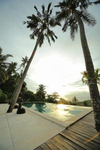 a swimming pool with two palm trees and the sunset at Villa Marley in Senggigi 