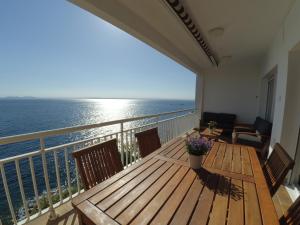 a balcony with a wooden table with a view of the ocean at Apartament Belvedere in Roses