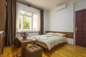 Schlafzimmer mit einem Bett, einem Tisch und einem Fenster in der Unterkunft Apart AS in Mostar