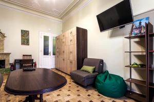 uma sala de estar com uma mesa e uma cadeira e uma televisão em Leosphere Hostel em Lviv