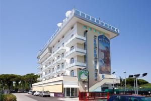 - un grand bâtiment blanc avec une bannière dans l'établissement Hotel Colombo, à Lido di Jesolo