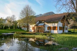 une maison avec un étang en face de celle-ci dans l'établissement Villa Anna Bad Goisern am Hallstättersee, à Bad Goisern