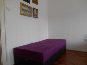 Cama morada en habitación blanca con cuadros en la pared en Dunavski Park, en Novi Sad