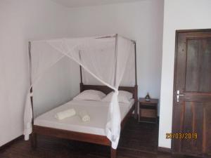 Schlafzimmer mit einem Bett mit Moskitonetz in der Unterkunft Tropic Hôtel in Ambondrona