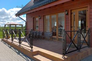 une maison en bois avec une terrasse munie de chaises. dans l'établissement Vila Viesai, à Trakai