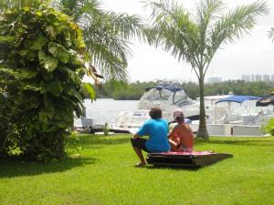 zwei Leute sitzen auf dem Gras in der Nähe eines Jachthafens in der Unterkunft Sotavento Hotel & Yacht Club in Cancún