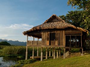 珍南海滩Bon Ton Antique Wooden Villas的河边茅草屋顶的小屋