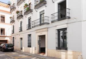 un bâtiment blanc avec balcon et une voiture garée dans une rue dans l'établissement ELEVEN Real de la Carretería, by Homing U, à Séville