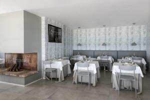 un restaurant avec des tables et des chaises blanches et une cheminée dans l'établissement Hotel Ristorante Centosedici, à Terracine