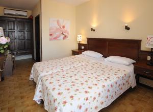 a bedroom with a large bed with a floral bedspread at Boutique Hotel Kentrikon & Bungalows in Agios Ioannis Pelio