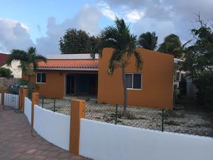 a house with a fence and palm trees at Luna 39 in Oranjestad