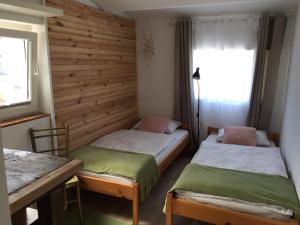 Duas camas num quarto com uma parede de madeira em Hillside Bio Resort Delux Apartments em Šešče pri Preboldu