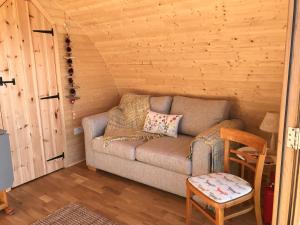 een woonkamer met een bank in een hut bij Sutor Coops The Den with Hot Tub in Cromarty