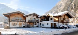 una casa en la nieve con coches aparcados delante de ella en Chalet Schnee, en Mayrhofen