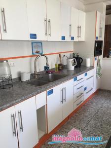 a kitchen with white cabinets and a sink at Hostal Magnolio in Viña del Mar