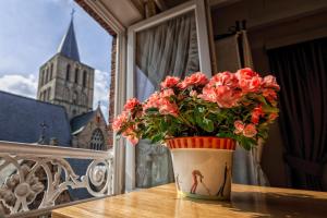 a vase with red flowers on a table with a church at Bariseele B&B in Bruges