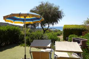 een blauwe en gele paraplu en een tafel en een bank bij Residence Baia Salinedda in San Teodoro