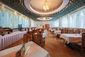 una sala da pranzo con tavoli, sedie e finestre di Hotel *** NAT Krynica Zdrój a Krynica-Zdrój