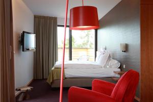 Habitación de hotel con cama y silla roja en The Seven Hotel, en Esch-sur-Alzette