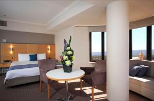 ein Hotelzimmer mit einem Bett und einem Tisch mit Blumen in der Unterkunft Stamford Grand Adelaide in Adelaide