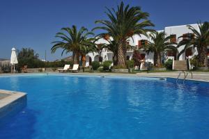 a large swimming pool with palm trees and a building at Eri Hotel in Parikia