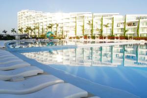 a swimming pool with lounge chairs in front of a building at AMAZING BEACH FRONT - ACQUA NUEVO VALLARTA - MX in Nuevo Vallarta 