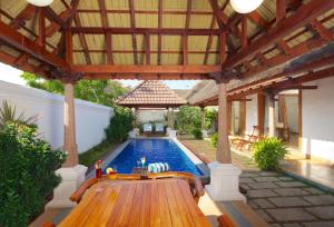 une piscine extérieure avec un banc en bois et un pavillon dans l'établissement Le Pondy, à Pondichéry