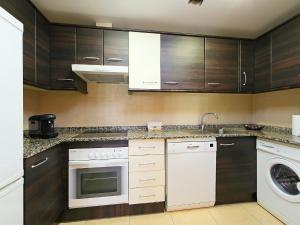 eine Küche mit weißen Geräten und Holzschränken in der Unterkunft Apartment Can Pavet by Interhome in Vilafortuny