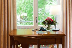 a wooden desk with a vase of flowers and a lamp at Landhaus Zu den Rothen Forellen in Ilsenburg