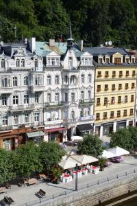 ein großes weißes Gebäude mit Tischen und Stühlen davor in der Unterkunft Hotel Palacky in Karlsbad