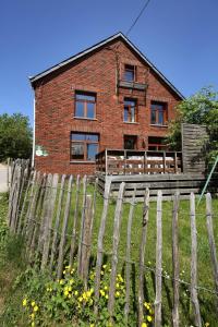 uma casa de tijolos com uma cerca de madeira em frente em Ferme Hurlet em Stavelot