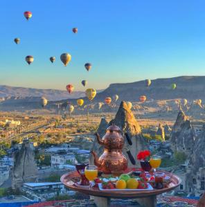 uma bandeja de comida com balões de ar quente no céu em Arif Cave Hotel em Goreme