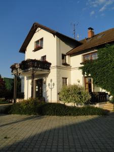 a white building with a balcony on the side of it at Villa Žerotín Penzion Bed & Breakfast in Velké Losiny