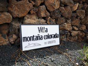 un cartello di fronte a un muro di pietra di Villa Montaña Colorada a Lajares