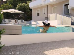 Un uomo con un cappello è in una piscina di Hotel Nettuno a Cala Gonone