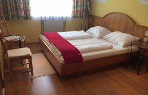 een slaapkamer met een bed, een raam en een stoel bij Hotel Pension Alte Mühle in Klosterneuburg