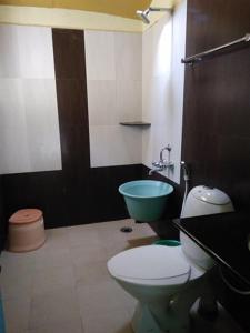 a bathroom with a toilet and a green sink at Thanmaya Homestay in Chikmagalūr