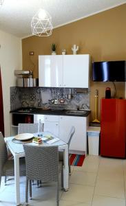 une cuisine avec une table et des chaises et une cuisine avec des placards blancs dans l'établissement Villa Sunset B&B/Apartments, à Fontane Bianche