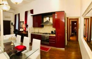 a kitchen with red cabinets and a table with white chairs at Colosseo Room in Rome