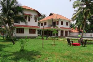 una casa con sillas en la hierba delante de ella en Water's Edge Villas, en Alleppey