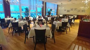 ein Restaurant mit weißen Tischen, Stühlen und Fenstern in der Unterkunft WAGNERS Sporthotel Oberhof in Oberhof