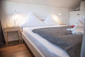 1 dormitorio con 1 cama grande con sábanas y almohadas blancas en Apartment JoniFee am Titisee, en Titisee-Neustadt