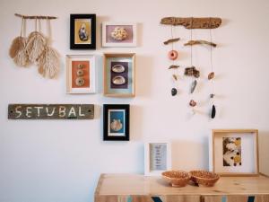 a room with a wall with framed pictures and a table at PEDRA DOS CORVOS Beach House in Odeceixe