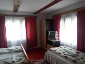 a hotel room with two beds and red curtains at Pensiunea Letitia in Suceviţa