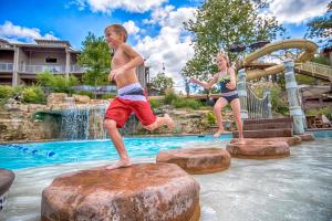 un garçon et une fille sautant sur un rocher dans une piscine dans l'établissement Still Waters Resort, à Branson