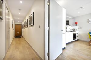 um corredor com paredes brancas e piso de madeira em Esquire Apartments Ealing em Londres