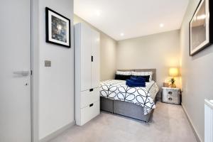 um quarto com uma cama e um armário branco em Esquire Apartments Ealing em Londres