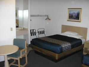 a bedroom with a bed and a table and chair at Mecca Motel in Colorado Springs