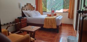 Un dormitorio con una cama y una mesa con un animal de peluche. en Hostal Vista Waynapata 123, en Machu Picchu