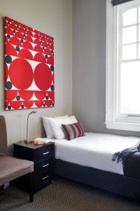 een slaapkamer met een bed en een rood schilderij aan de muur bij Vulcan Hotel Sydney in Sydney